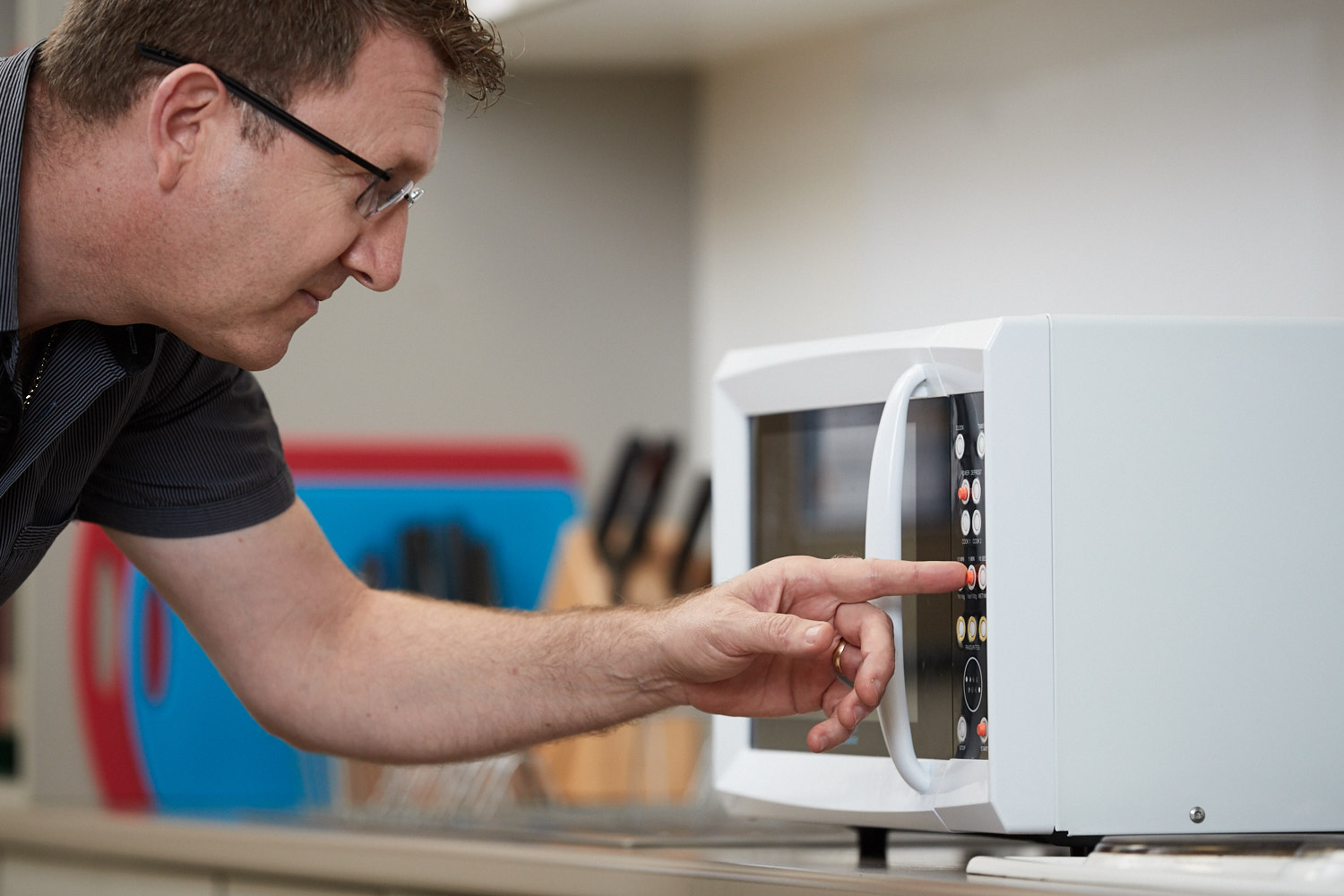 A man uses a microwave fitted with tactile dots