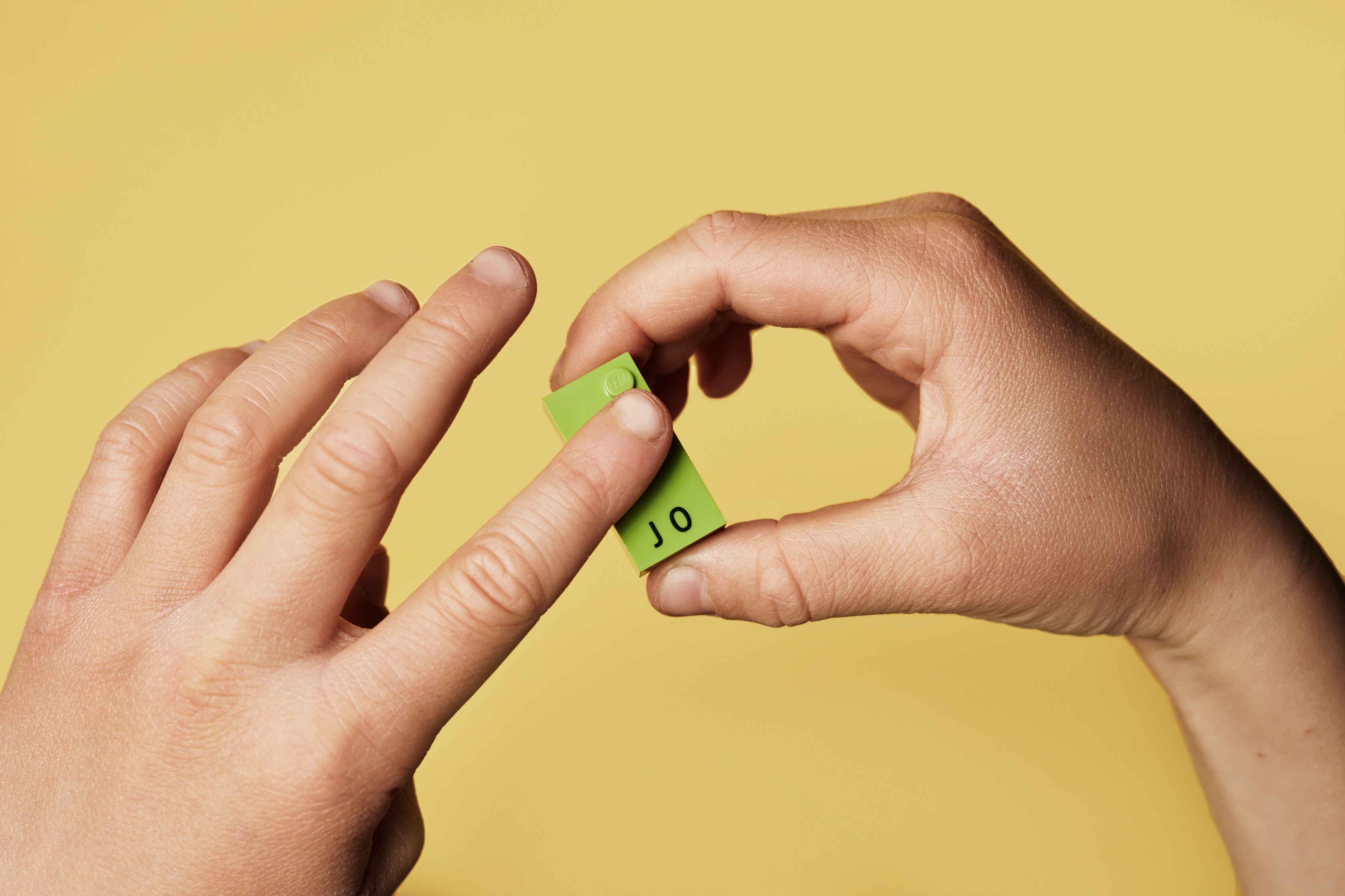 Fingers feeling the raised braille dots on the LEGO brick