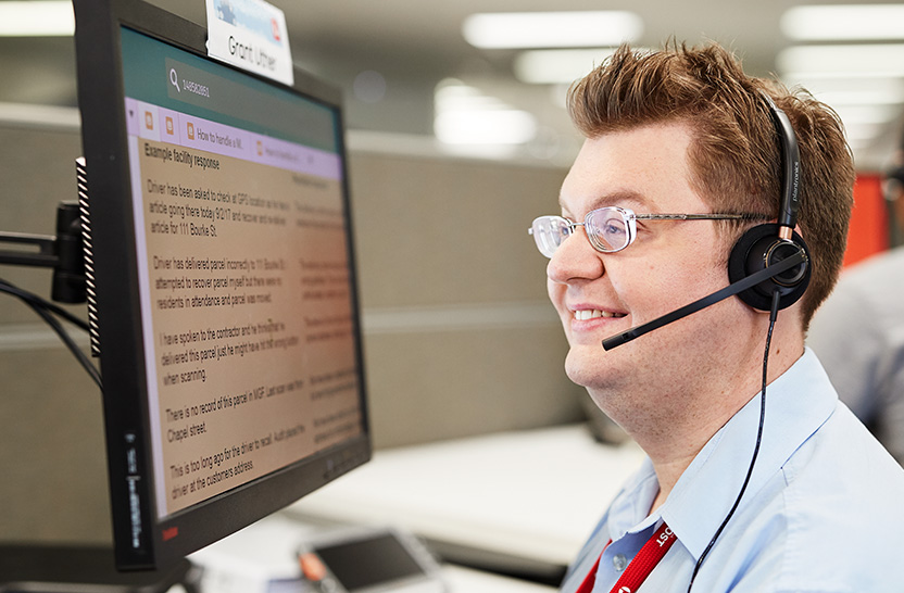 Call centre staff member wearing a headset looks at computer screen that has magnification applied.