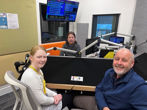 Three people sit in a radio studio