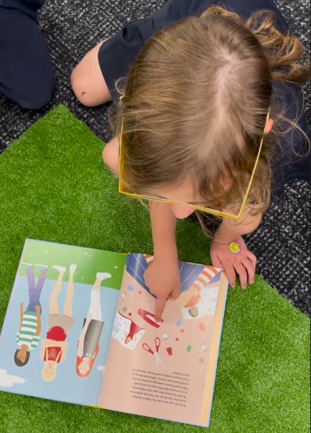 "A child looks at a copy of Dressed for Success, pointing at the page"