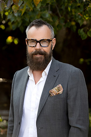 Vision Australia GM National Programs and Client Insights Graeme Craig is looking at the camera with a slight smile. He has glasses, a beard and is wearing a dark grey suit with white shirt.