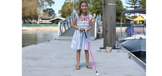 Kaylah standing with her cane