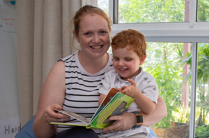 Hugo sits with his mum Katie, reading books from Vision Australia's Feelix library
