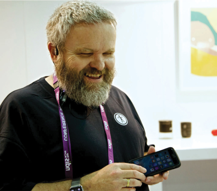 David Woodbridge smiiling while holding a smart phone device.