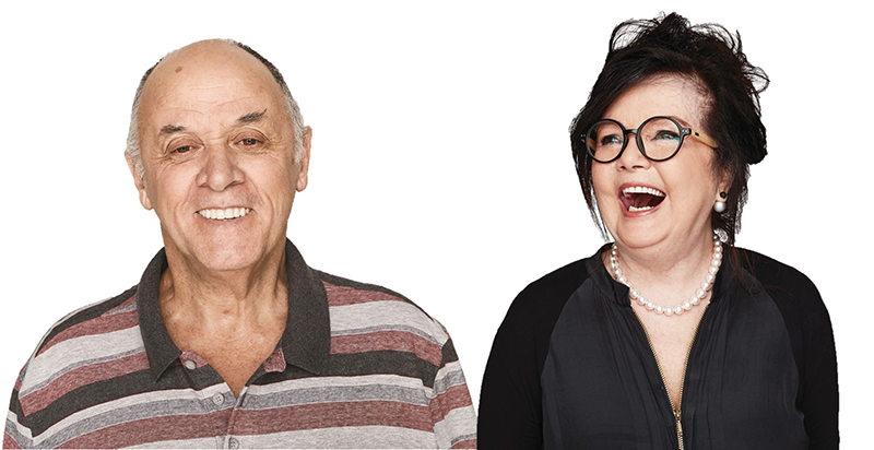 A man is smiling to camera and a woman wearing glasses is looking up and laughing