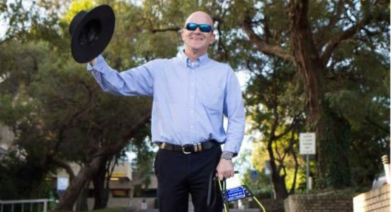 Rolf, Regional Business Manager A middle-aged man wearing sunglasses is smiling while holding out a black hat