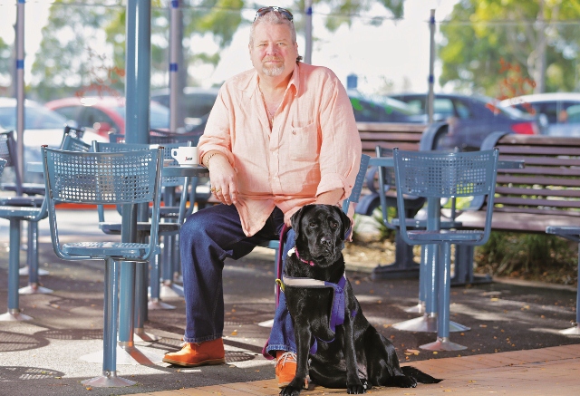 John is sitting chair outside with black labrador, Seeing Eye Dog, Umali