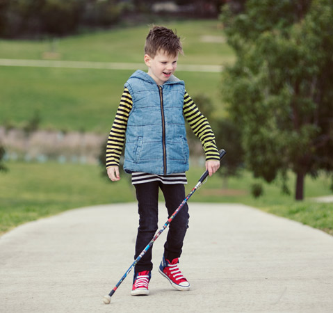 Max walks along a path in the park, using his white cane