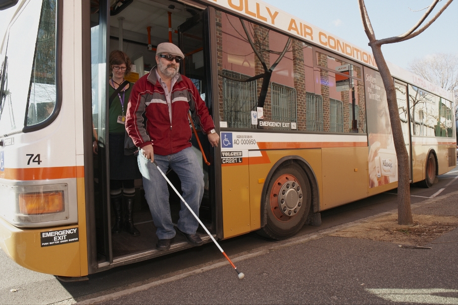 Person with long cane disembarking from a bus