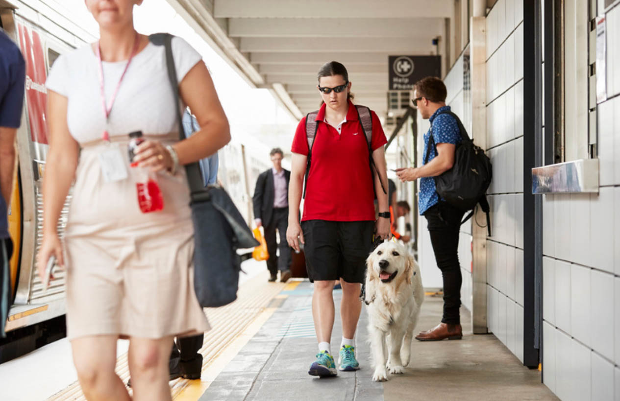 A student walking with her seeing eye dog at a train station