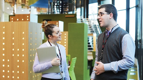 A man and a women stand in an office hallway