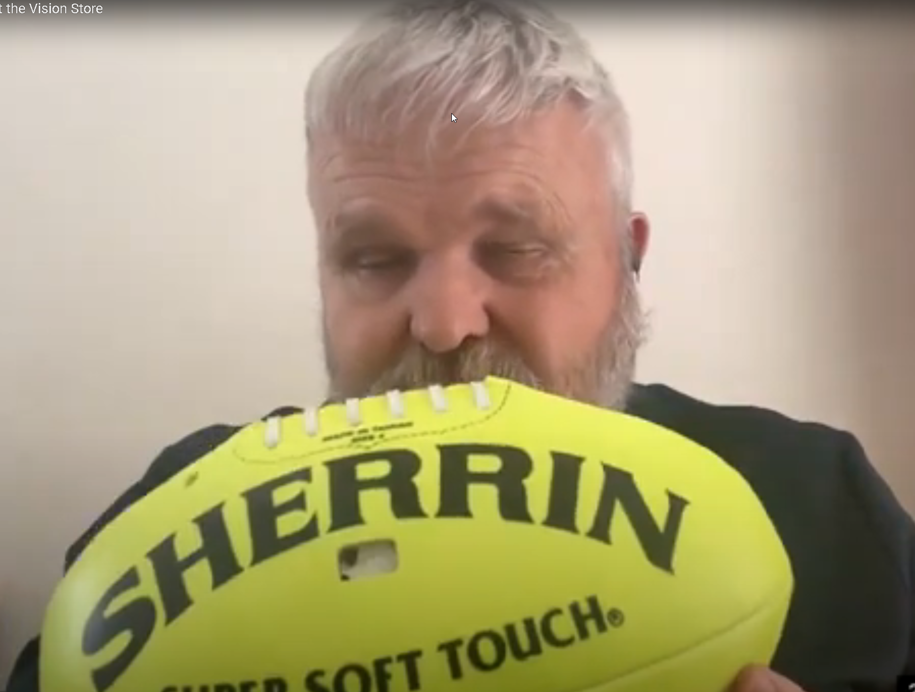 David Woodbridge holding a yellow AFL football up the the camera