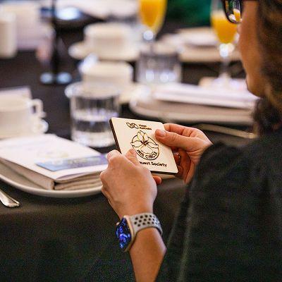 A guest holds a coaster with the words 'Iris Circle' engraved on it.