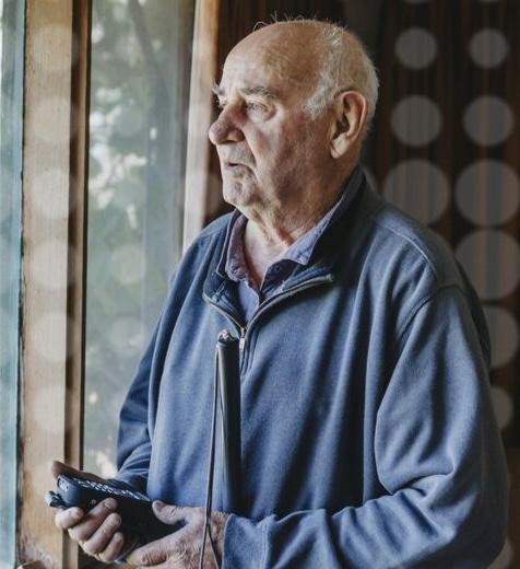 An older gentleman is looking out the window.